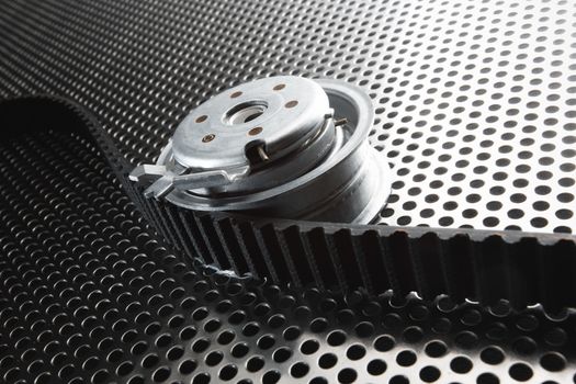 Bearing tensioner and timing belt on a metal surface. Photo from the vignetting effect