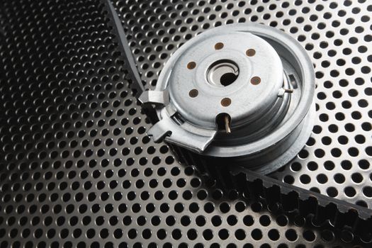 Bearing tensioner and timing belt on a metal surface. Photo from the vignetting effect