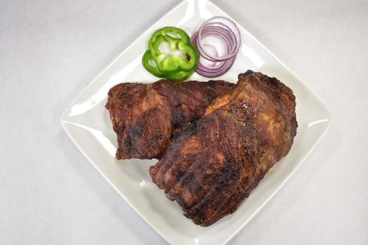 A Well-Done Rack of Ribs Plated on a White Background