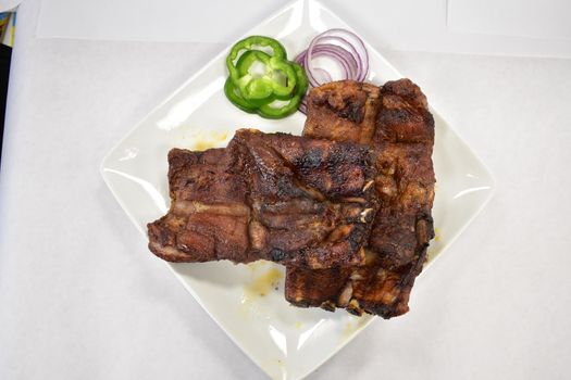 A Well-Done Rack of Ribs Plated on a White Background