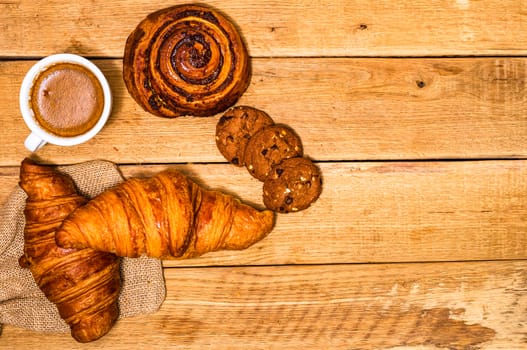 Fresh croissant and biscuits on wooden table. Coffee, food and breakfast concept. Desserts, fresh pastries and coffee. Top view and copy space