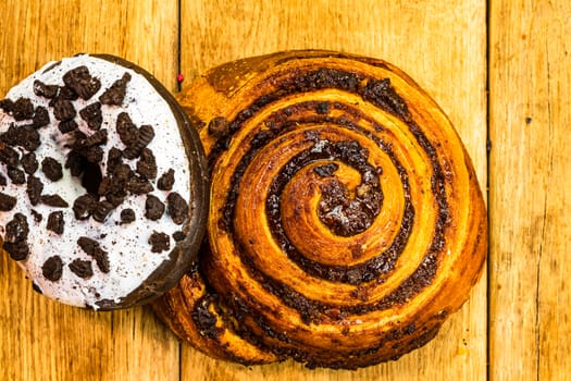 Colorful donuts on wooden table. Sweet icing sugar food with glazed sprinkles, doughnut with chocolate frosting. Top view with copy space