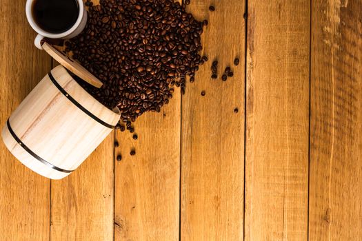 Cup of coffee, roasted coffee beans on wooden background, coffee wooden barrel top view, copy space for text, close up coffee photo