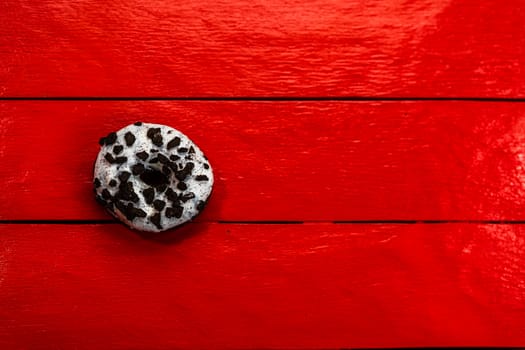 Colorful donuts on red wooden table. Sweet icing sugar food with glazed sprinkles, doughnut with chocolate frosting. Top view with copy space