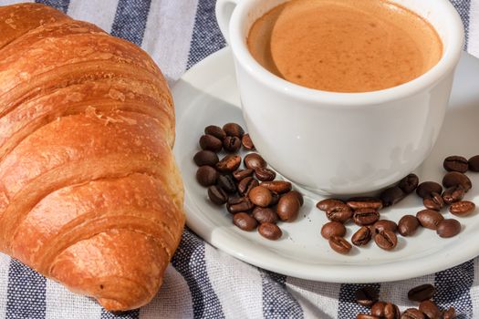 Puff pastry, coffee cup and buttered French croissant on wooden crate. Food and breakfast concept. Detail of coffee desserts and fresh pastries