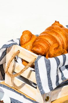 Fresh croissant, puff pastry and buttered french croissant on wooden crate. Food and breakfast concept. Detail of desserts and fresh pastries