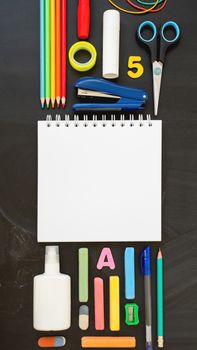 Top view on colorful stationery. Back to school flat lay concept. Vertical blackboard background with copy space. 9-16 ratio for mobile applications.