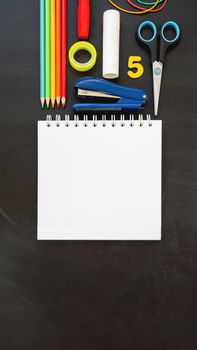 Top view on colorful stationery. Back to school flat lay concept. Vertical blackboard background with copy space. 9-16 ratio for mobile applications.