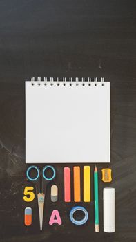 Top view on colorful stationery. Back to school flat lay concept. Vertical blackboard background with copy space. 9-16 ratio for mobile applications.