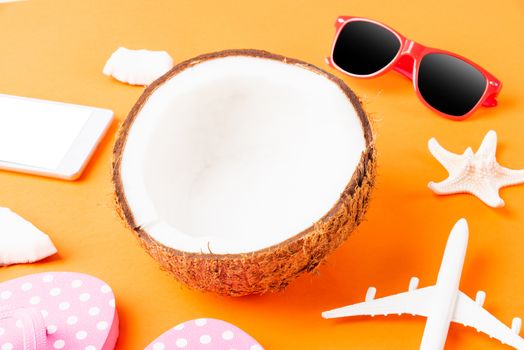 Happy coconuts day concept, fresh coconut, and summer accessories (model plane, sunglasses, smartphone, starfish and slippers), Beach tropical fruit trip journey and spring-summer holiday