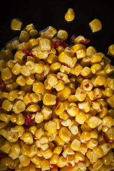 Tinned corn with pepper on a black plate