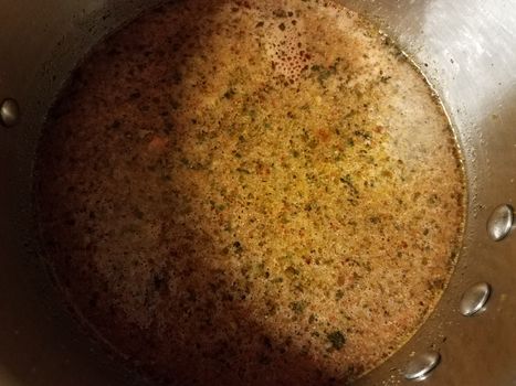 seasoned hot broth liquid in metal pan or pot