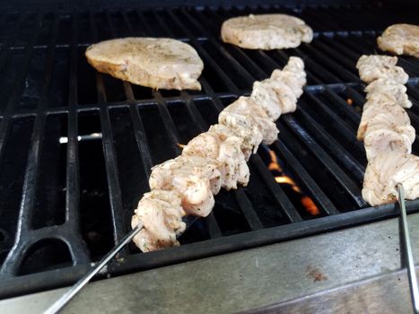 raw chicken meat on metal skewer on barbecue grill