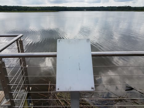 blank and worn metal plaque on railing with river or stream water