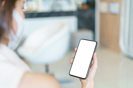 Woman wearing protective mask showing smart phone blank screen.