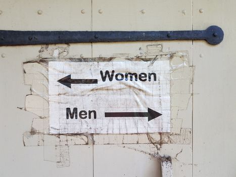 white wood door with men and woman bathroom sign and arrows