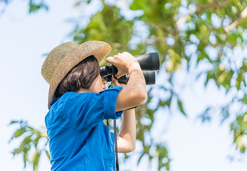 Close up Young asian woman short hair wear hat and hold binocular in grass field countryside Thailand