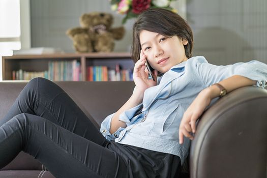 Close up young asian woman short hair use mobile phone on the couch in living room at home