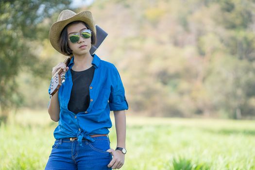 Young asian woman short hair wear hat  and carry her guitar  in grass field countryside Thailand