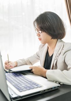 Woman teenage short hair in smart casual wear working on laptop while sit near window in home office