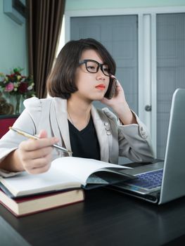 Woman short hair in smart casual wear working on laptop while sitting near window in home office