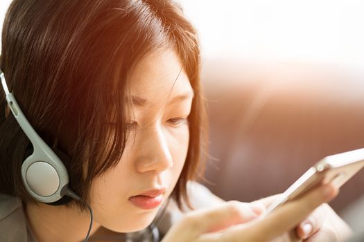 Close up young asian woman short hair listening music from mobile phone on the couch