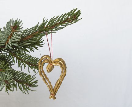 Christmas decoration straw heart on silver spruce tree branch on white background