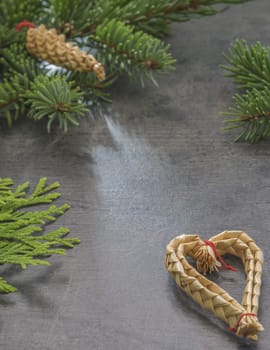 vertical christmas decoration frame fir branch and straw heart on gray texture background