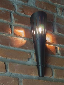black iron electric torch light on the red brick wall background