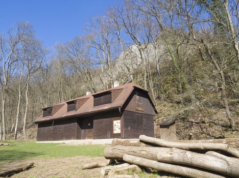 old log cabin in spring forest with rocks and trees in the countryside of central Bohemian region on on spring sunny day, blue sky.