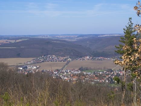 view on village in brdy in czech republic with trees, buildings and hills, early spring, blue sky background