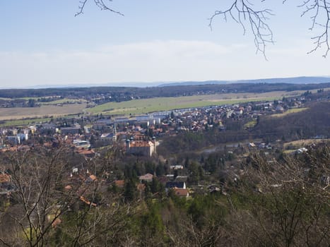 view on small city mnisek pod brdy in czech republic with trres, castle and buildings, early spring, blue sky background