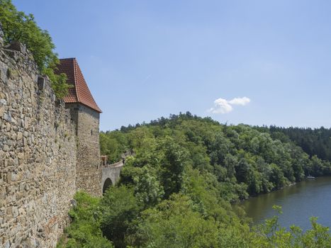 view from rampart of medieval castle Zvikov (Klingenberg), wall with tower, vltava river, spring green trees and blue sky, Czech Republic