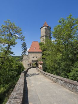 medieval castle Zvikov (Klingenberg) main entry gate with round tower and stone bridge, green trees and blue sky, castle is placed at confluence of the Vltava and Otava rivers, South Bohemian Region, Czech Republic, vertical view