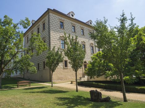 Czech Republic, Benatky nad Jizerou, July 28, 2018: Renaissance style castle with Sgraffito decorated facade, park, footpath, green trees garden and wooden bench, sunny summer day