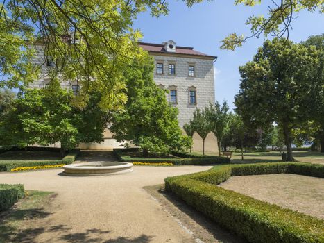 Czech Republic, Benatky nad Jizerou, July 28, 2018: Renaissance style castle with Sgraffito decorated facade, park, footpath, fountain, green trees garden and wooden bench, sunny summer day