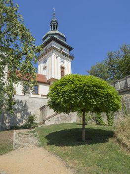 Czech Republic, Benatky nad Jizerou, July 28, 2018: old town hall tower in castle park Benatky nad Jizerou with footpath, stair, green trees, sunny summer day, blue sky background