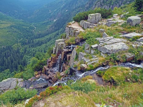 pancava waterfall on krkonose mountains with big rock and forest valley