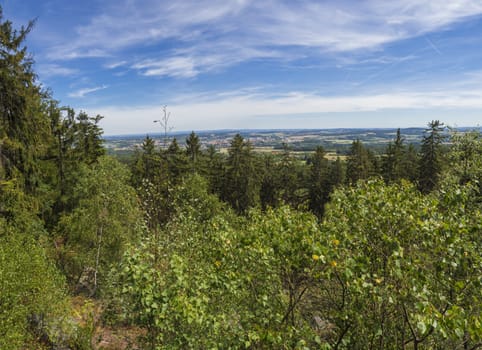 Panoramic view from look out in Brdy mountain hills, with green trees, rocks town and blue sky, Czech Republic.