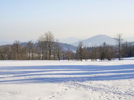 winter field and forest countryside snow covered landscape with trees, hill and wooden high seat in luzicke hory lusatian mountains.