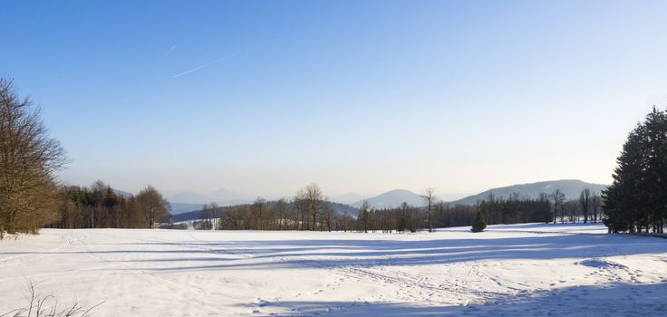 winter field and forest countryside snow covered landscape with trees, hill and wooden high seat in luzicke hory lusatian mountains.