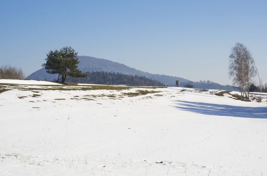 winter field and forest countryside snow covered landscape with trees, hill and wooden high seat in luzicke hory mountain.