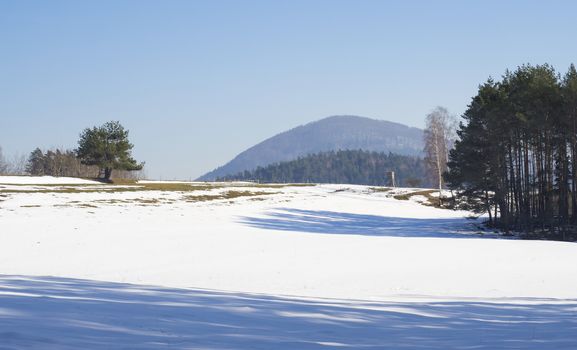 winter field and forest countryside snow covered landscape with trees, hill and wooden high seat in luzicke hory mountain.
