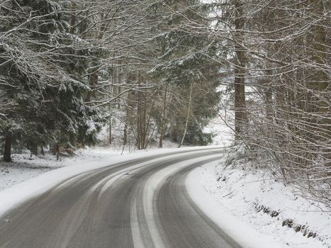 snow covered asphalt road curve in winter forest