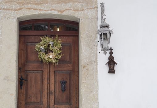 old wooden door with sandstone lining, wreath, lantern and cross on white background
