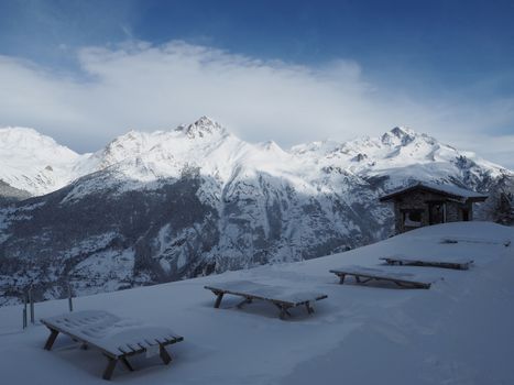 Alpine mountain view in europe winter snow with snow covered picnic table