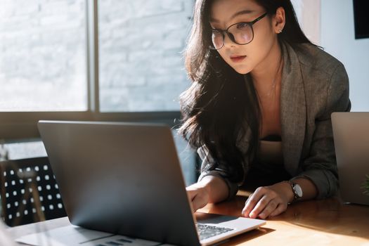 Young Asian Businesswoman on laptop computer in office.