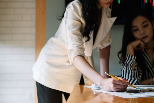 Business people meeting in office and discussing over a documents, two woman with a financial report with partner colleague on laptop computer.