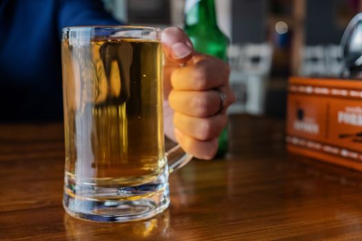 Man's hand holding beer glass