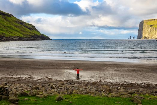 Tourist standing at the beach in Tjornuvik located on the coast of a beautiful bay in the Faroe Islands, Denmark.